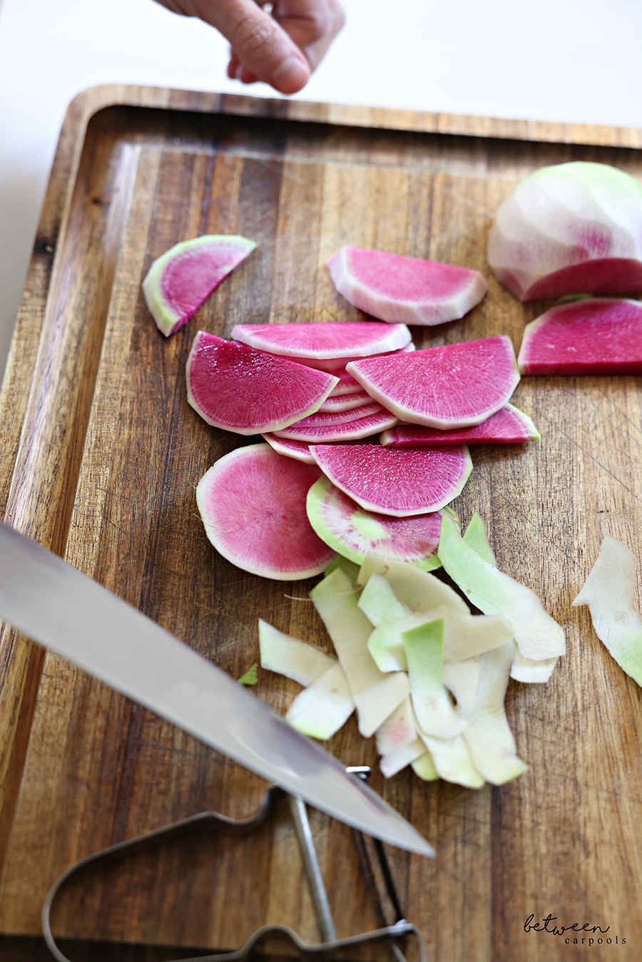 thinly sliced half rounds of watermelon radish on a wooden cutting board