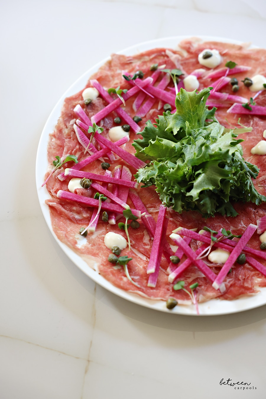 Full plate of carpaccio garnished with fresh parsley, closeup view