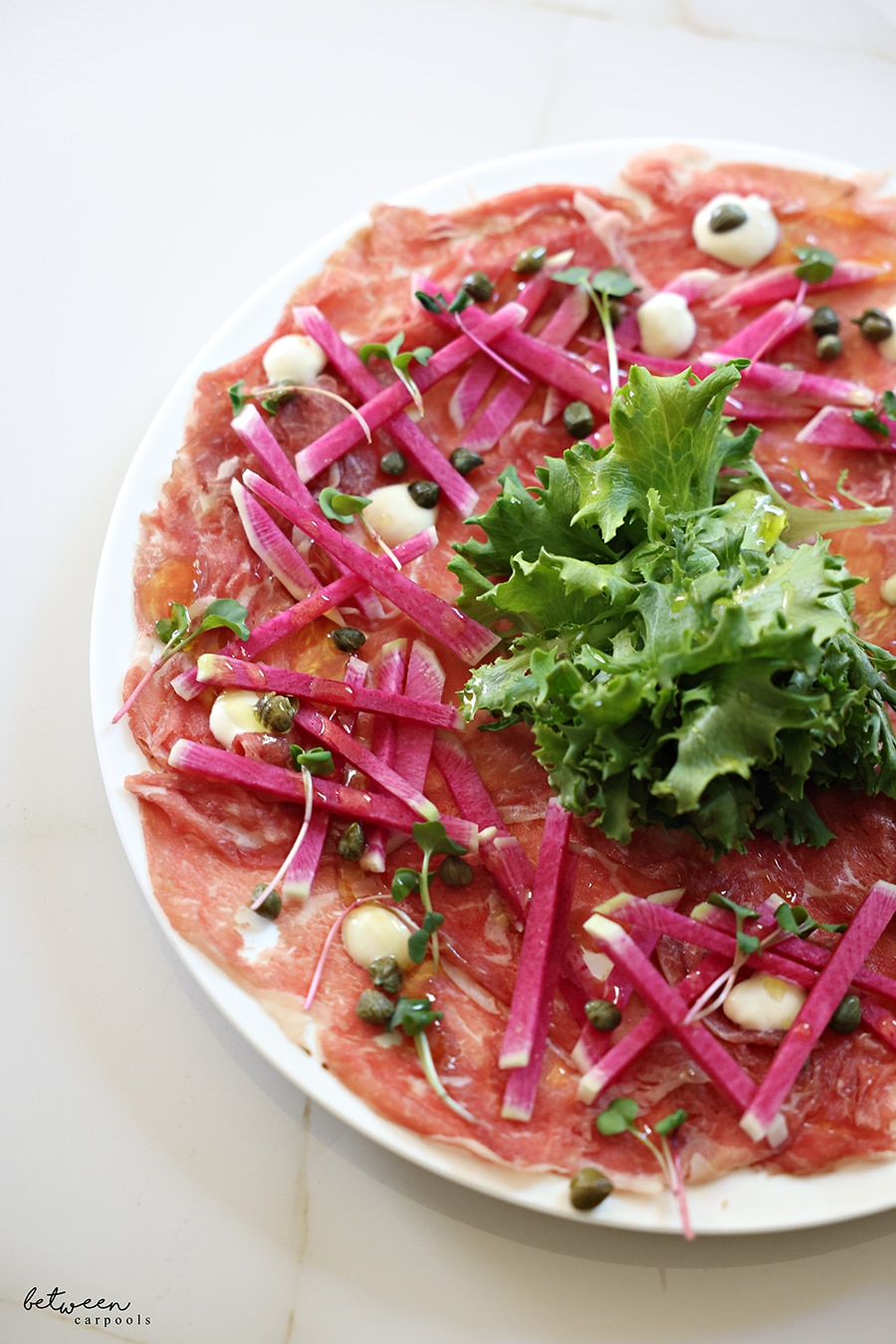 Full plate of carpaccio garnished with fresh parsley, closeup view