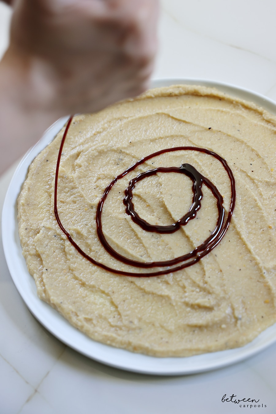 drizzling silan on plated creamy eggplant