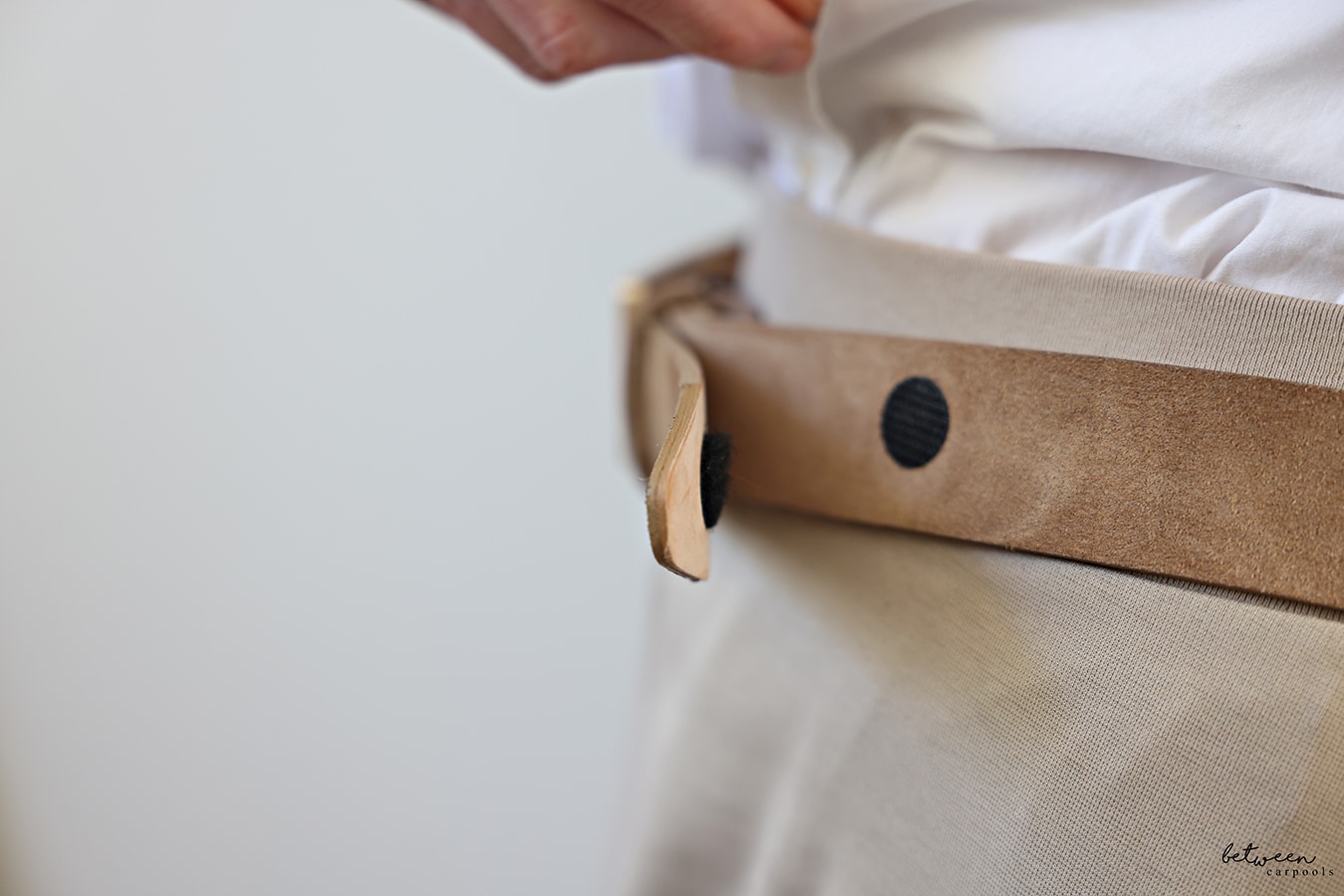 woman wearing a belt with an added velcro circle. extra belt flap shown with velcro attached