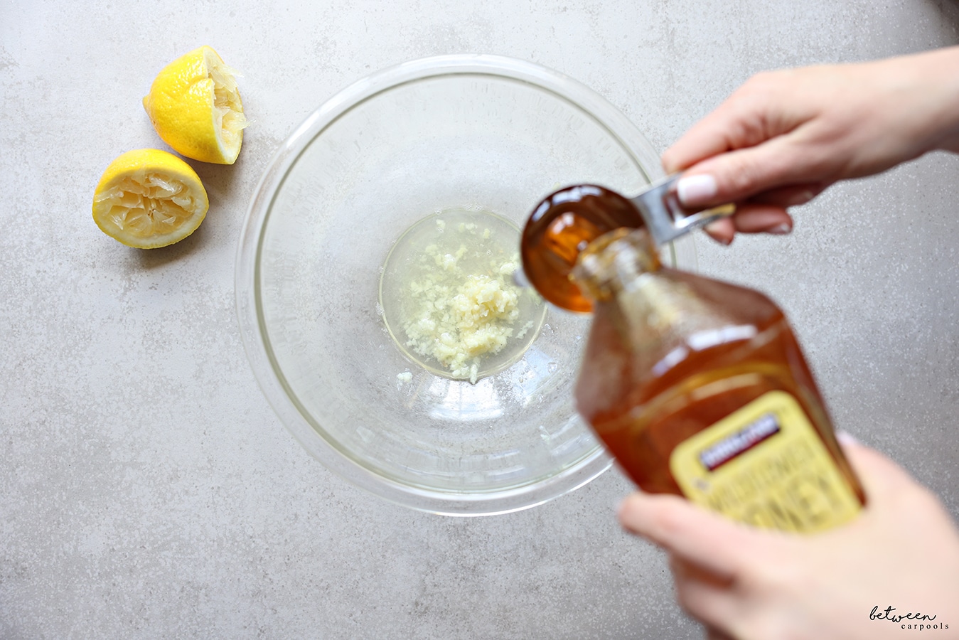 adding honey to the ingredients for marinade in a glass mixing bowl