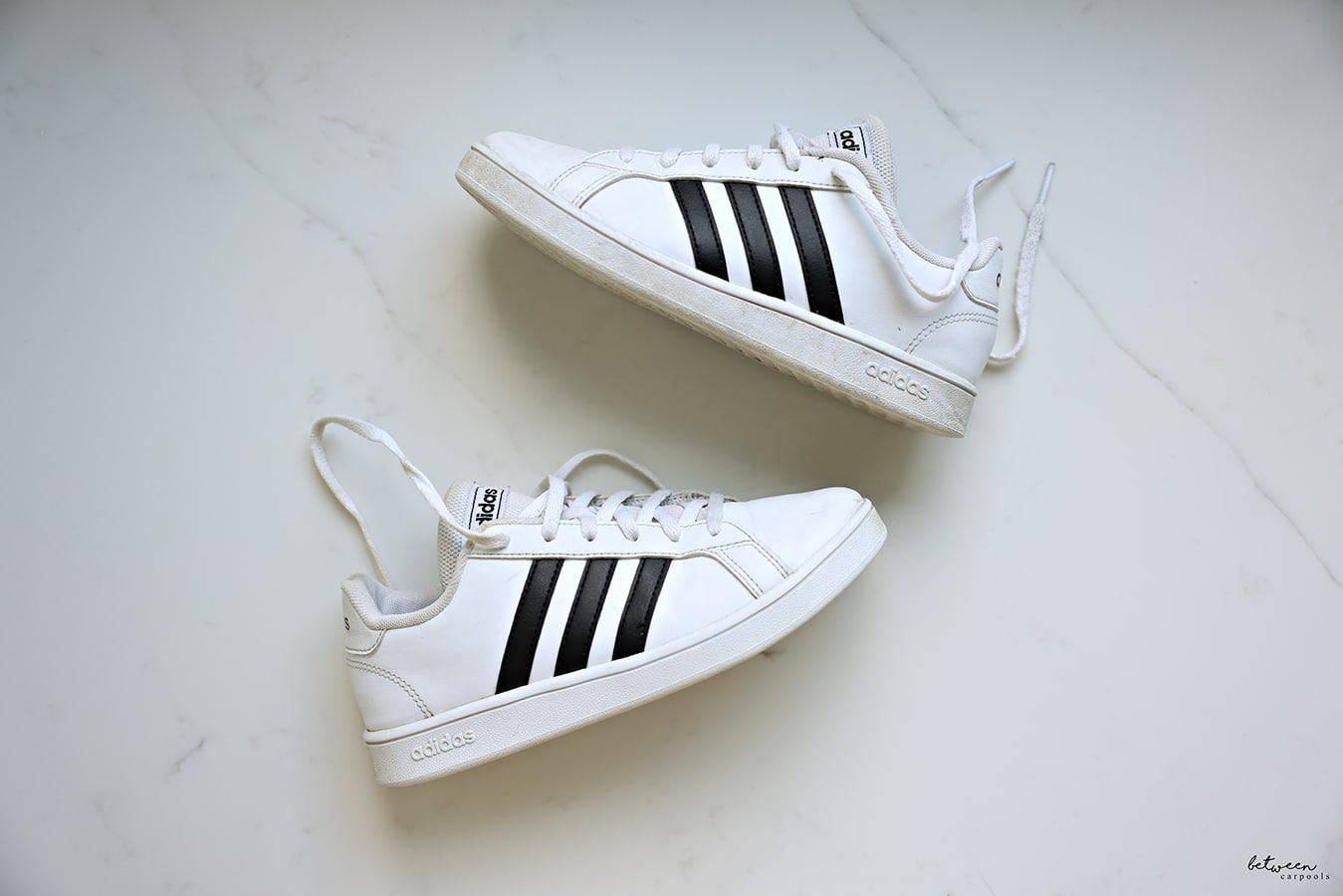 A pair of adidas girls white sneakers, the before and after of cleaning them