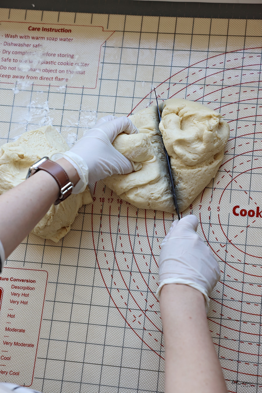 dividing kokosh cake dough for 4 rolls - with gloved hands, on a baking mat