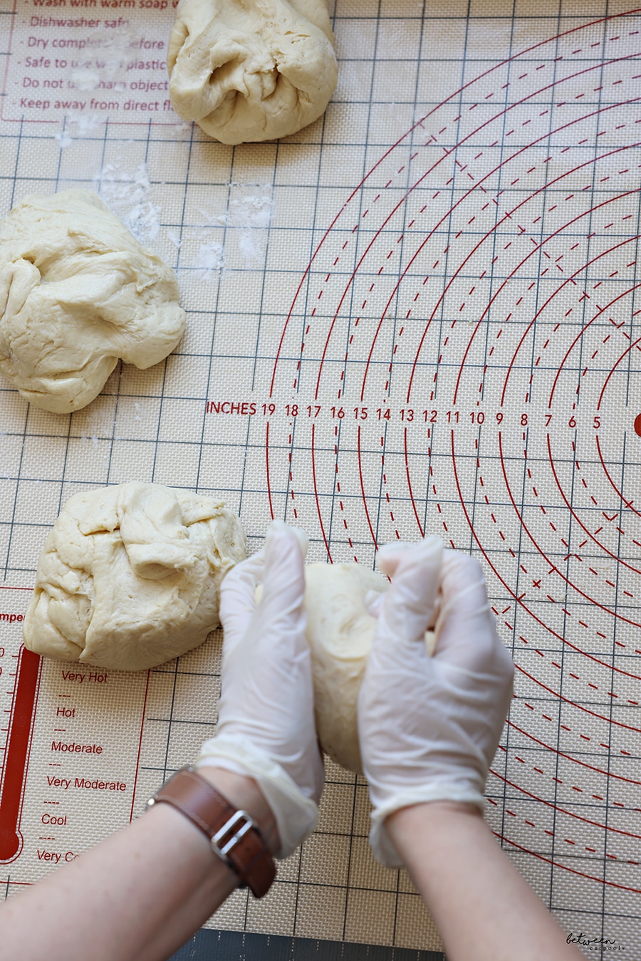 a ball of kokosh cake dough in my gloved hands - on a baking mat. 3 balls of dough on the side