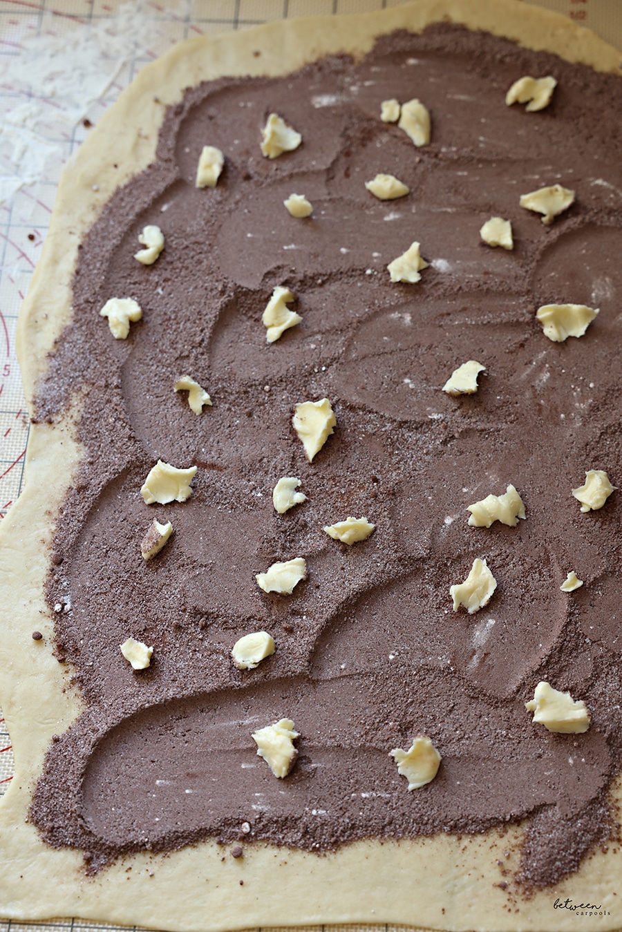 dots of butter scattered across the rolled kokosh dough sprinkled with cocoa + sugars