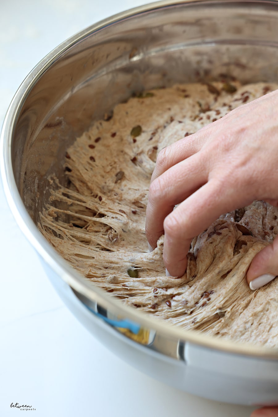 Separating No Knead Artisanal Bread dough in a metal bowl into two loaves