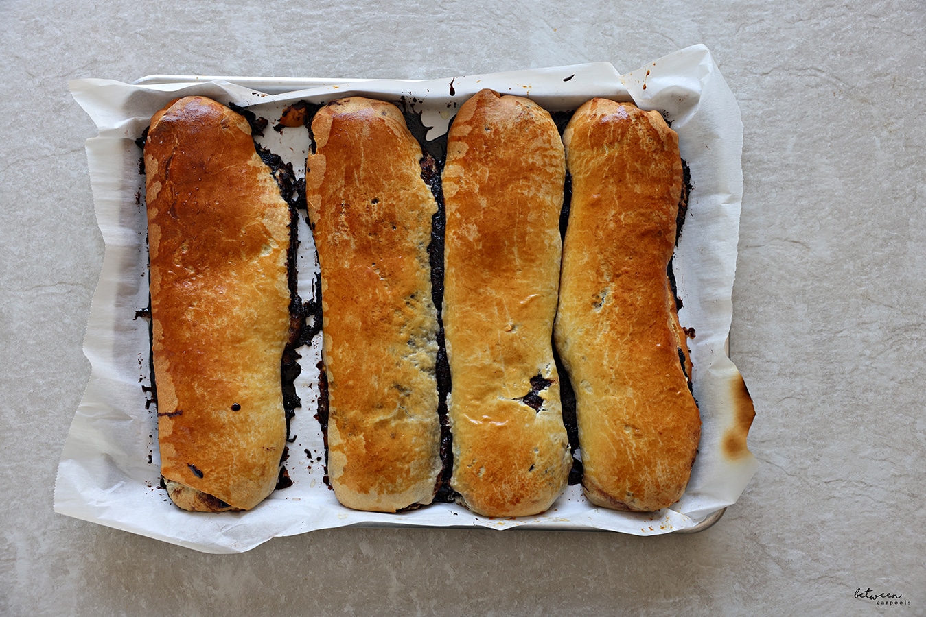 4 baked kokosh cake rolls on a parchment lined baking sheet