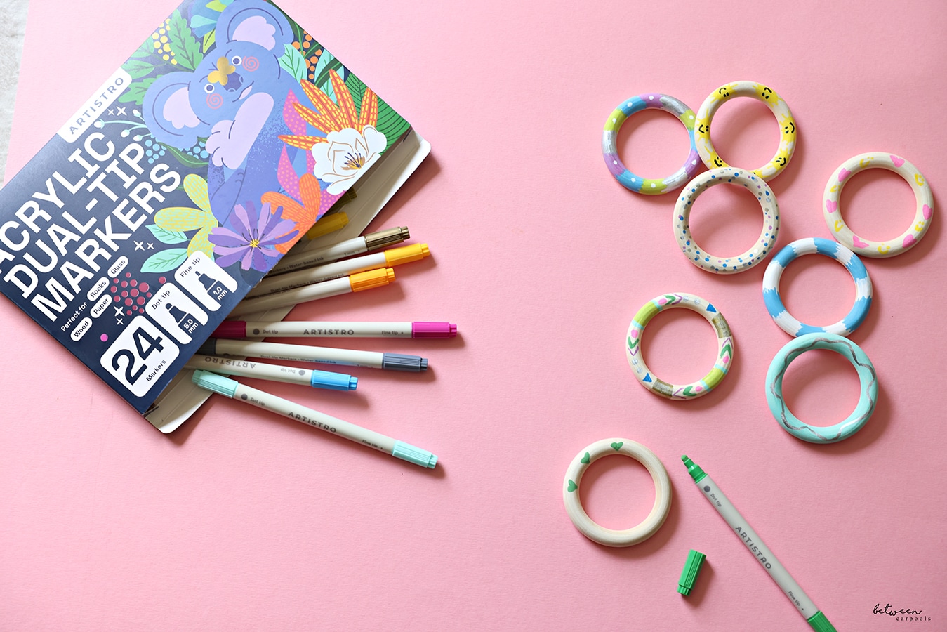 wooden rings and paint markers on pink background