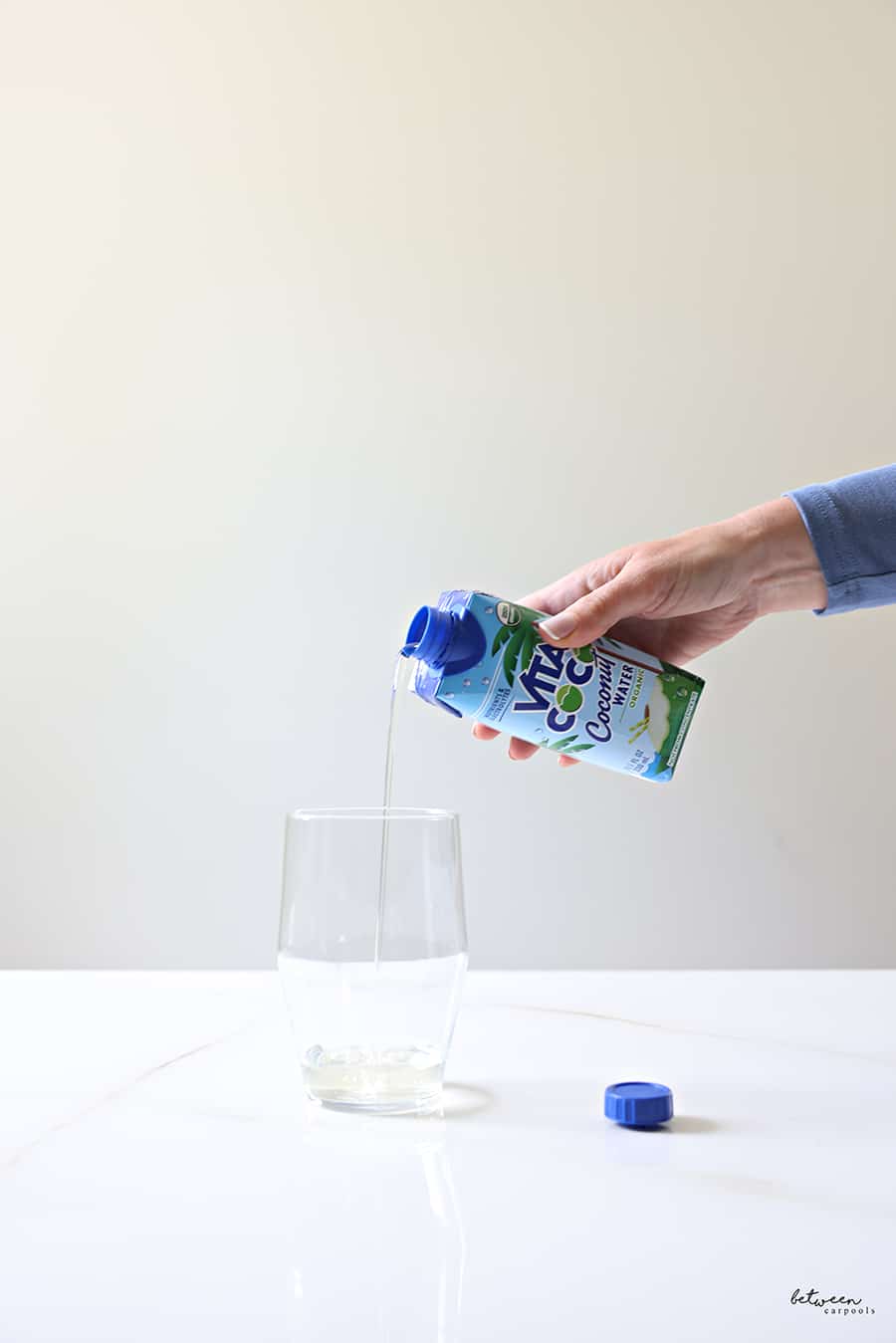 pouring coconut water into a glass with ice
