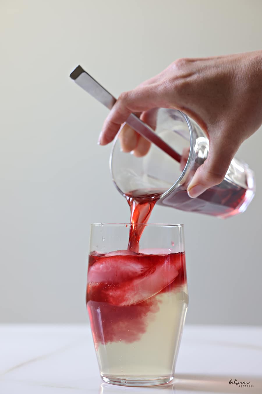 adding tea concentrate to a glass with coconut water and ice
