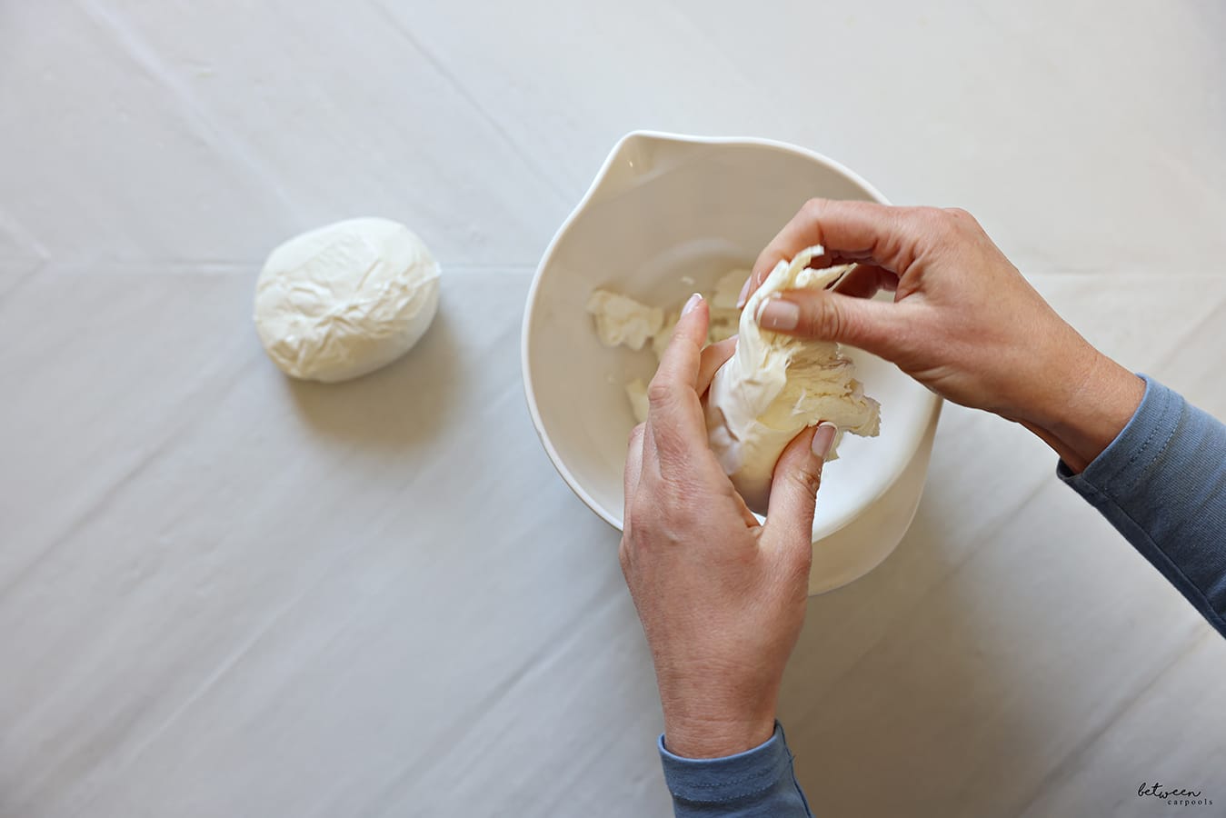 shredding fresh mozzarella cheese into a spouted mixing bowl