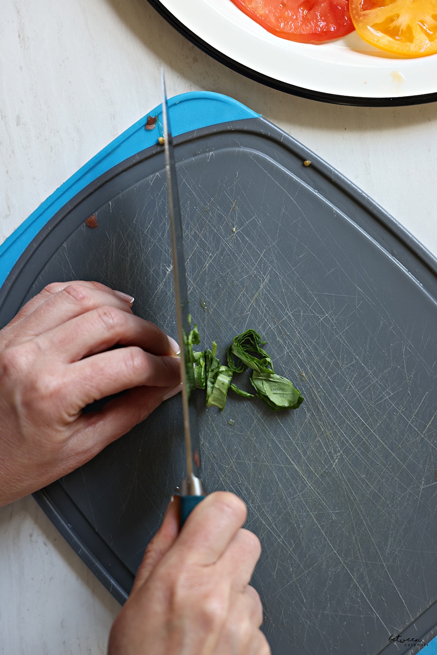slicing rolled basil leaves on a cutting board