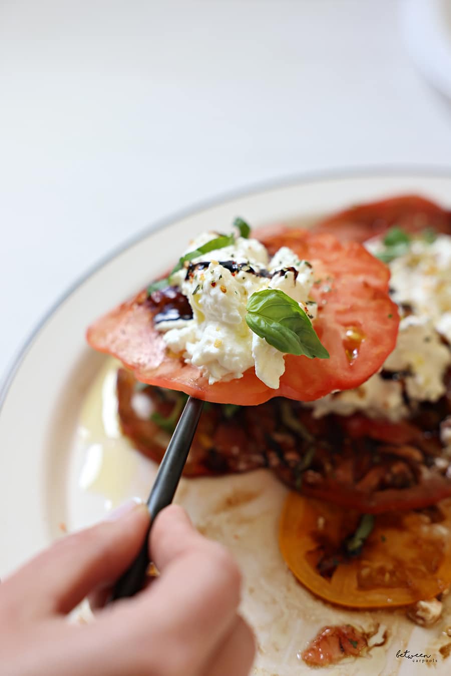 a tomato with all toppings on a fork