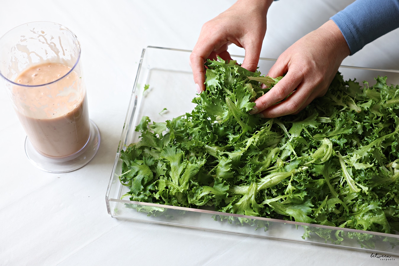 Adding salad greens to a lucite platter.