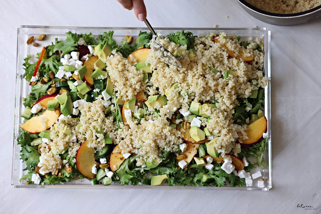 bulgar added to salad greens + cucumbers, nectarines, nuts, avocado and feta on a lucite platter.