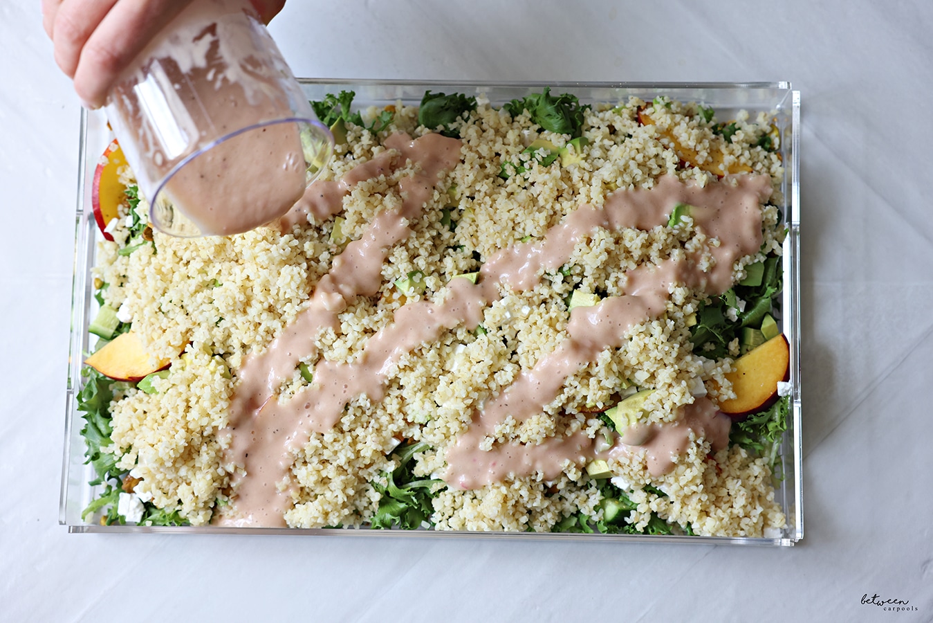 Pouring dressing onto the salad on a lucite platter.