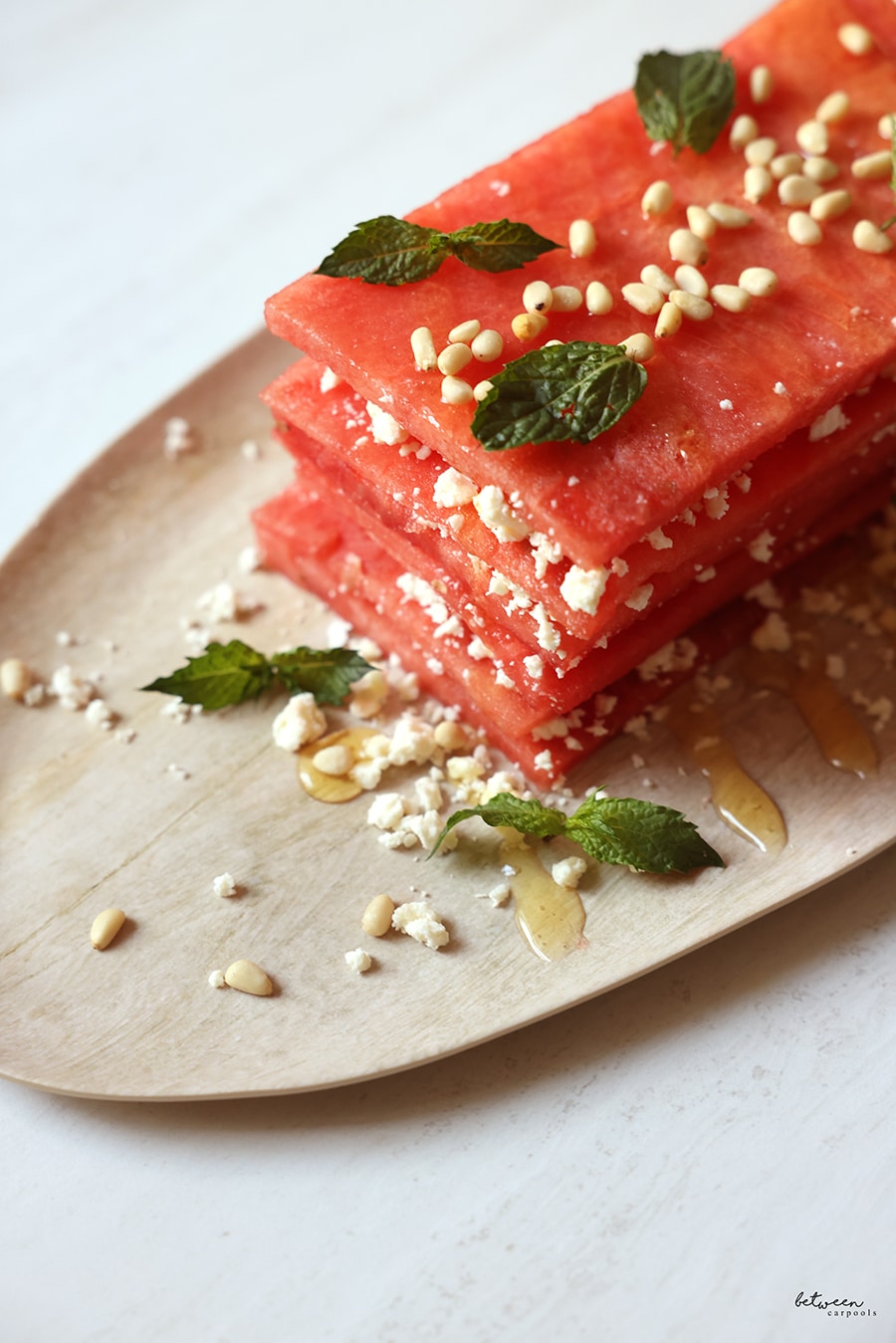 Watermelon and feta topped with honey, some nuts, and mint leaves