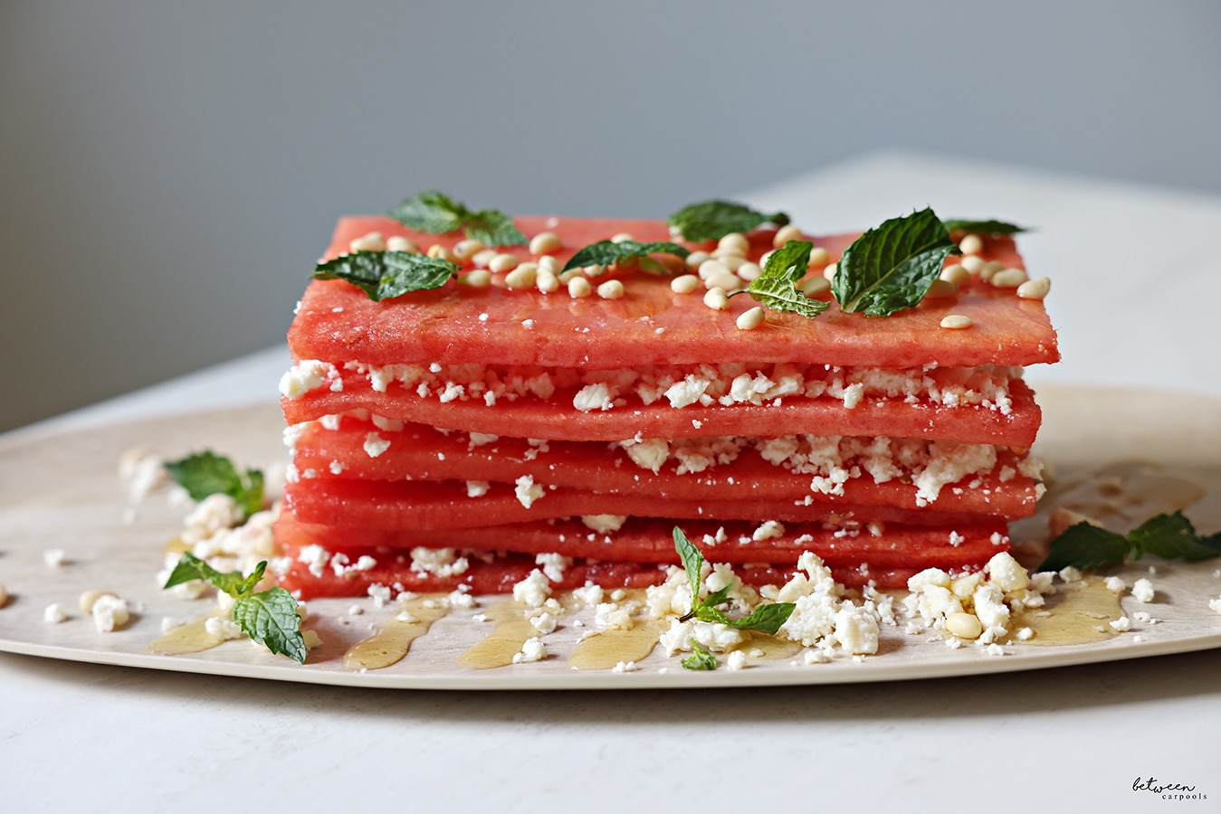 Watermelon and feta topped with honey, some nuts, and mint leaves