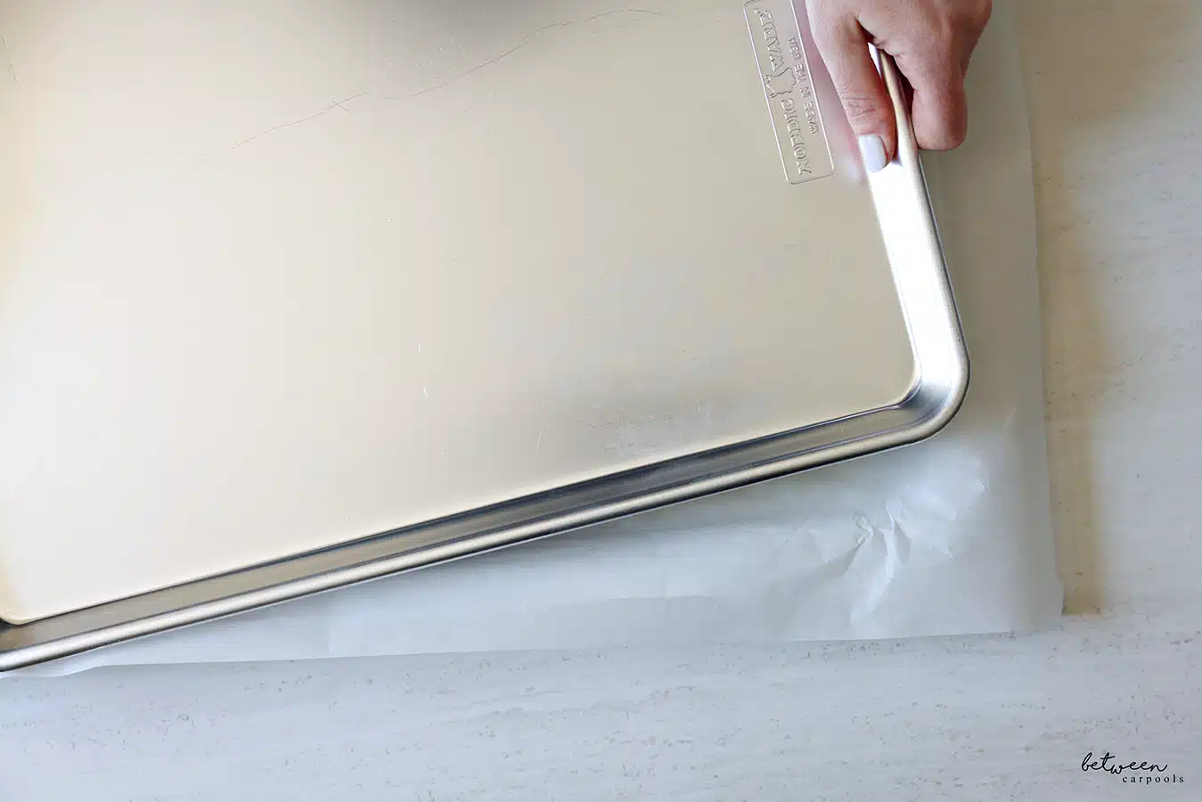 Placing a metal baking sheet on top of the parchment paper covering the layer of sushi rice on a parchment lined metal sheet pan.