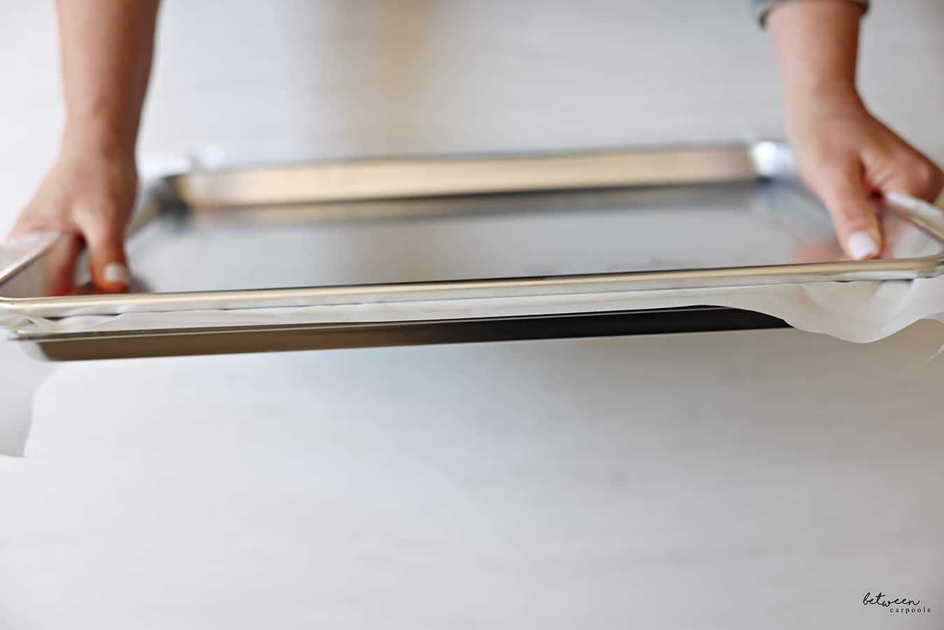 Pressing down on the metal baking sheet on top of the parchment paper covering the layer of sushi rice...