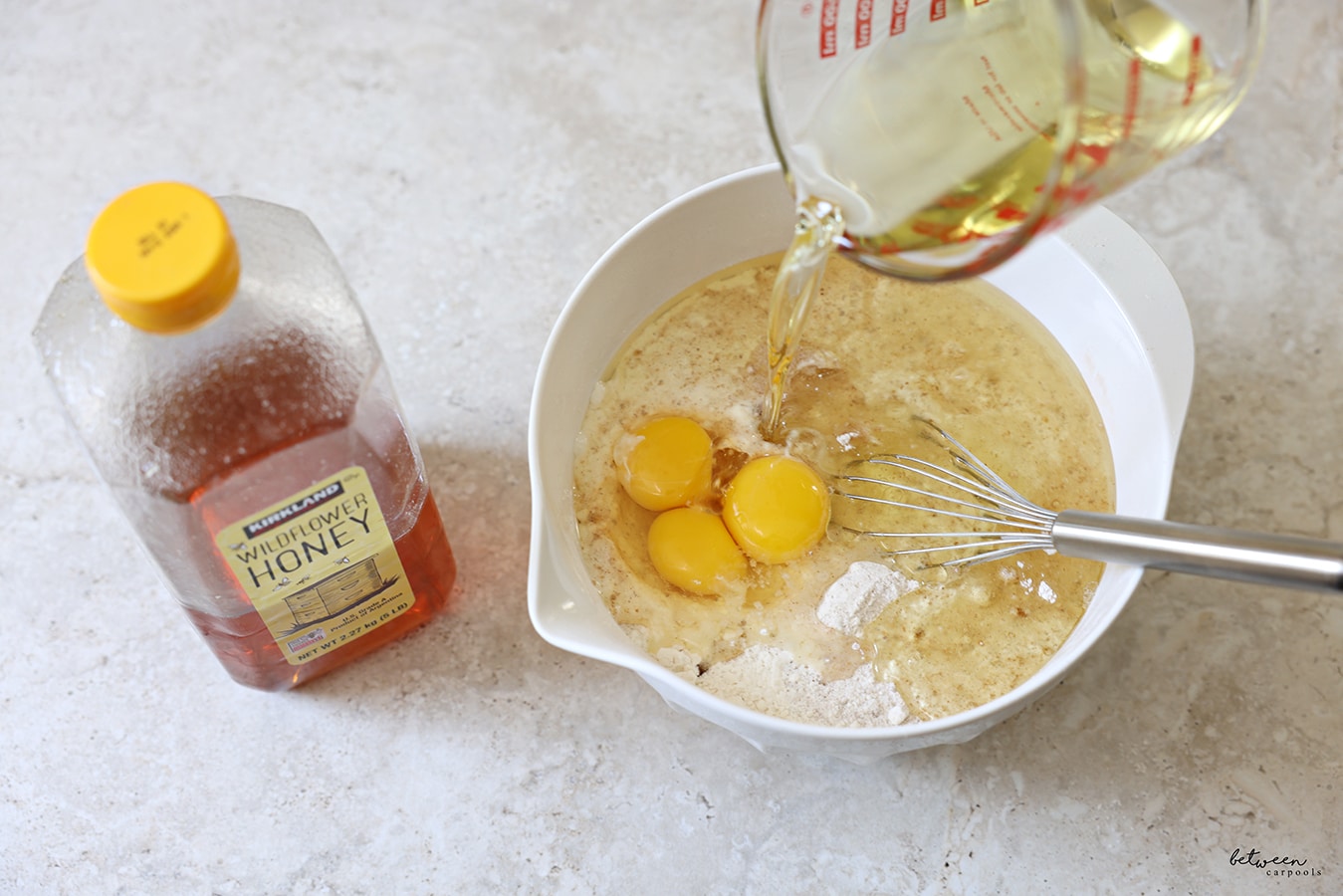 Adding wet ingredients into the mixing bowl with all dry ingredients mixed together