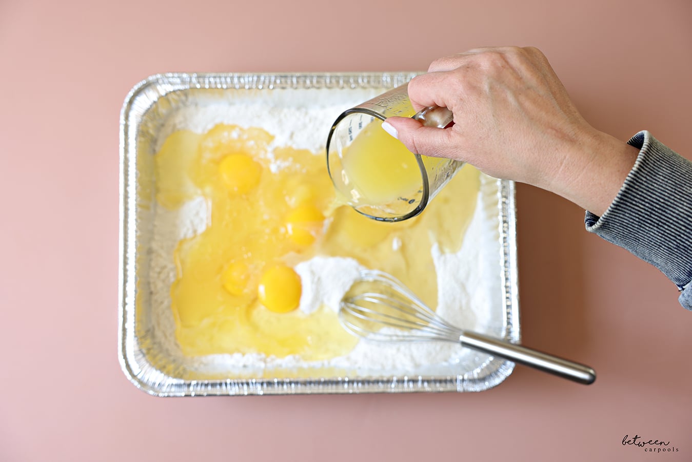 Adding the wet ingredients to the dry ingredients in a 9x13 disposable foil pan.