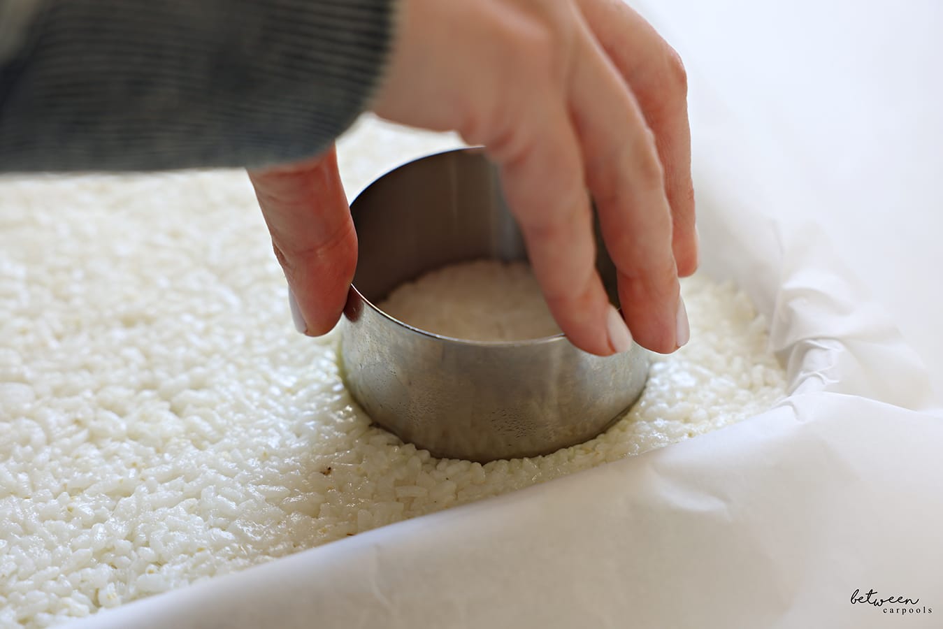 Using a deep cookie cutter to cut rice cakes from the layer of sushi rice.