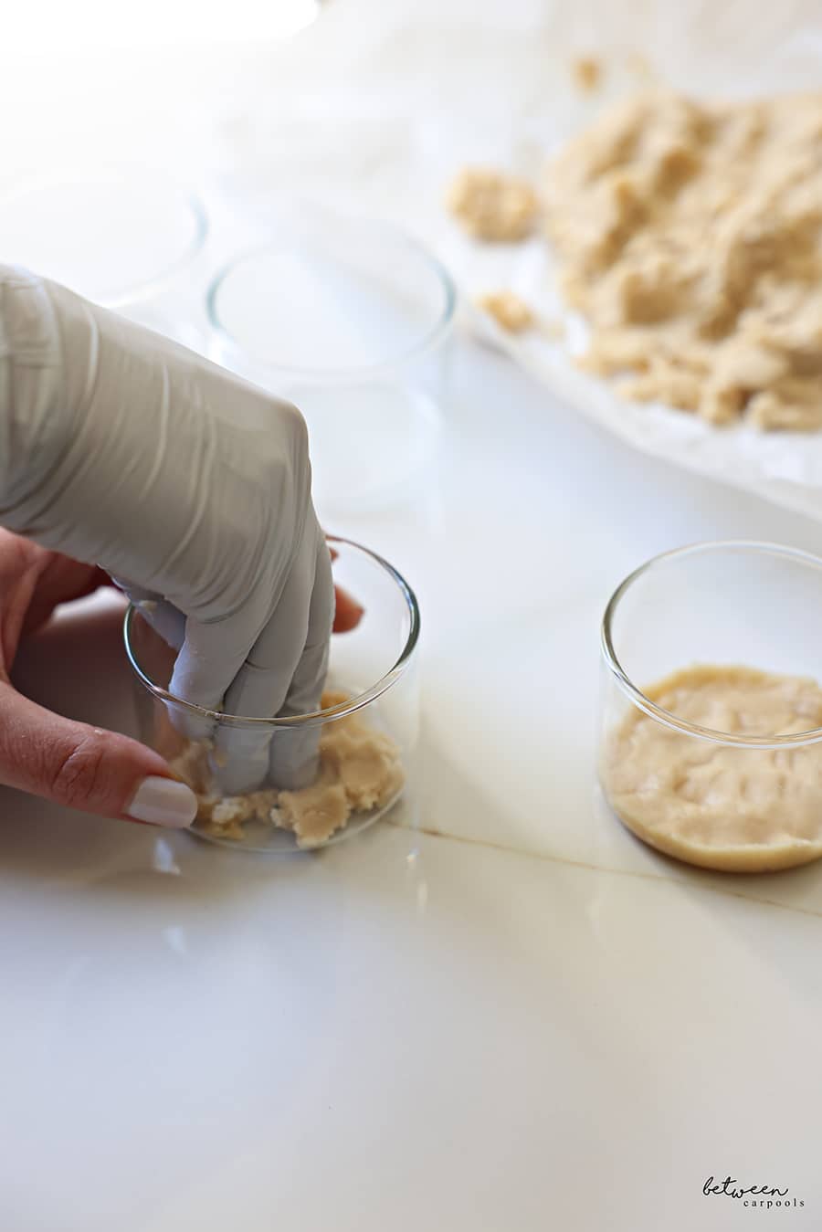 Pressing the shortbread cookie base into each ramekin - with a gloved hand