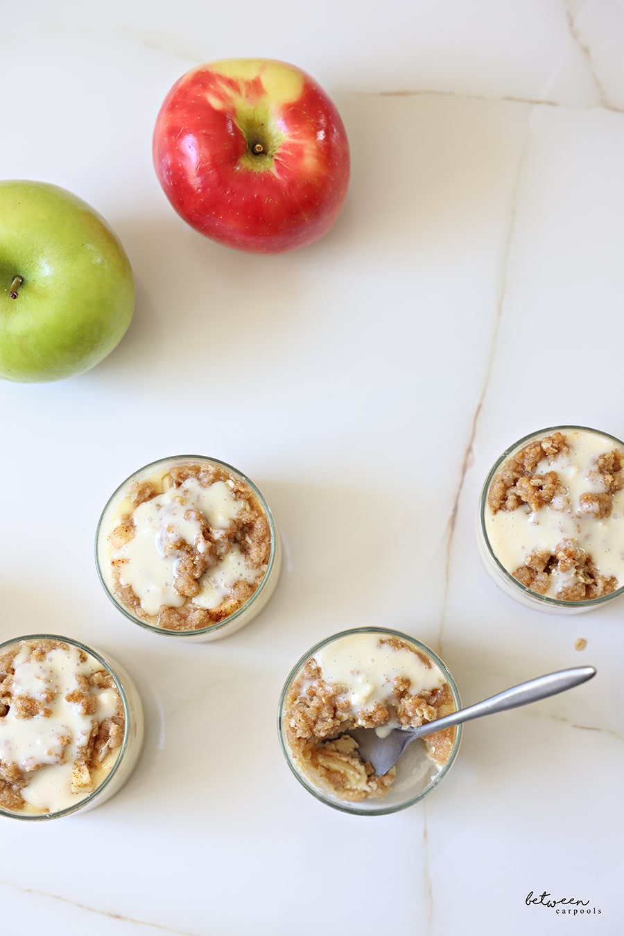 Top view of baked apple cheesecake ramekins - a bite out of/a spoon in one