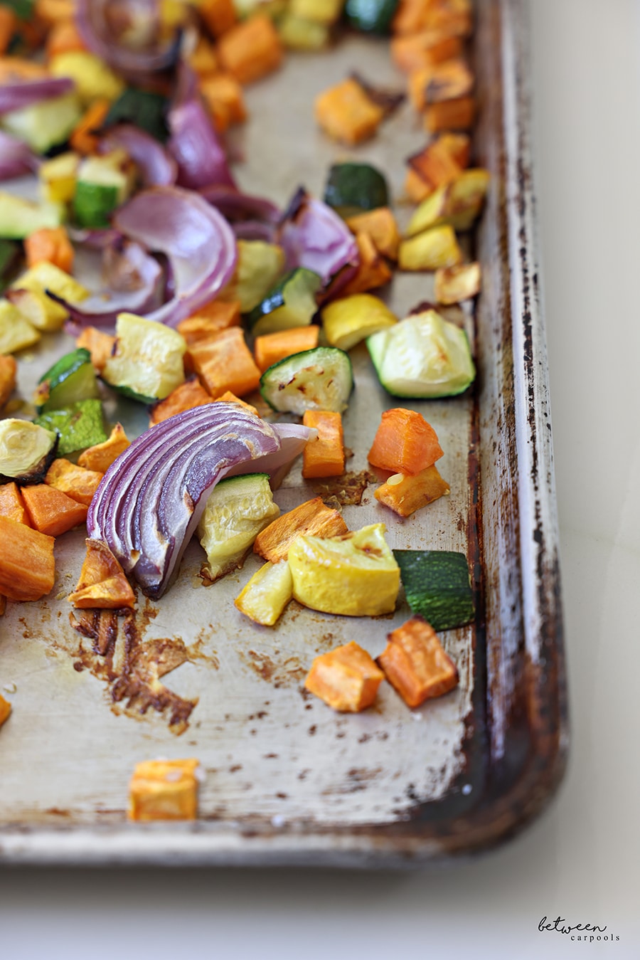 Closeup of roasted vegetables on a metal sheet pan.