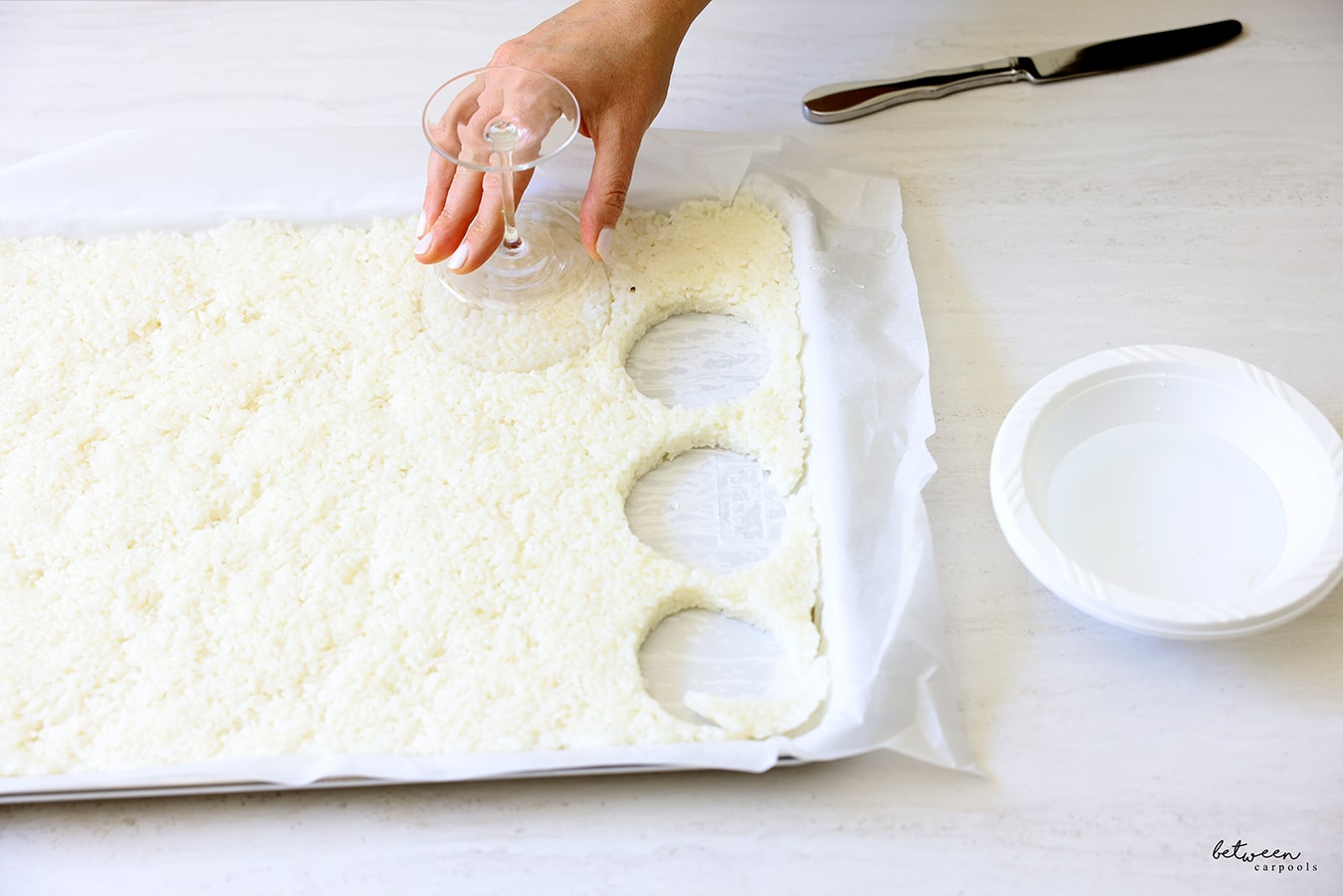 Using a glass to cut rice cakes from the layer of sushi rice.