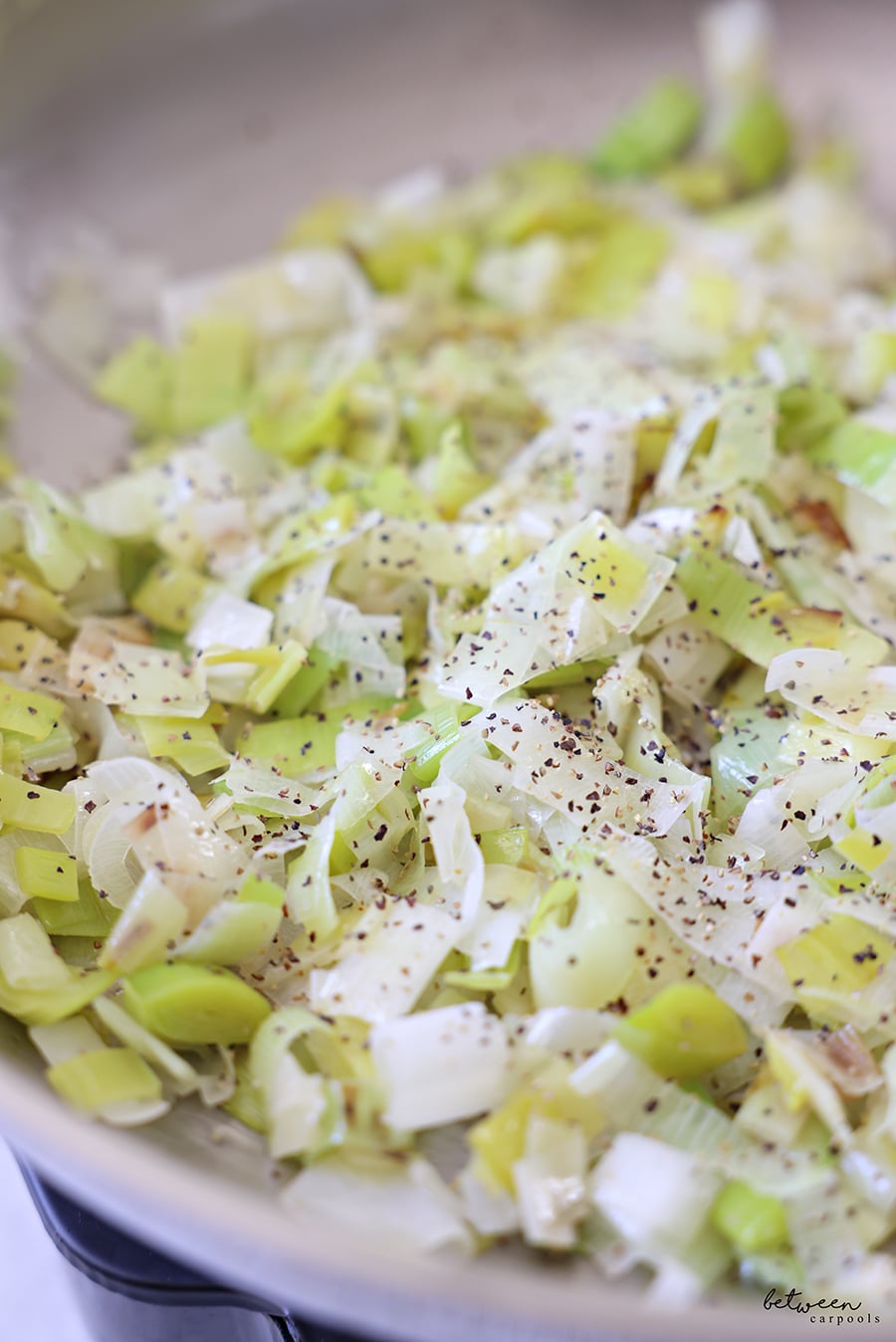 Leeks in a pan with olive oil and seasoned with salt and pepper.