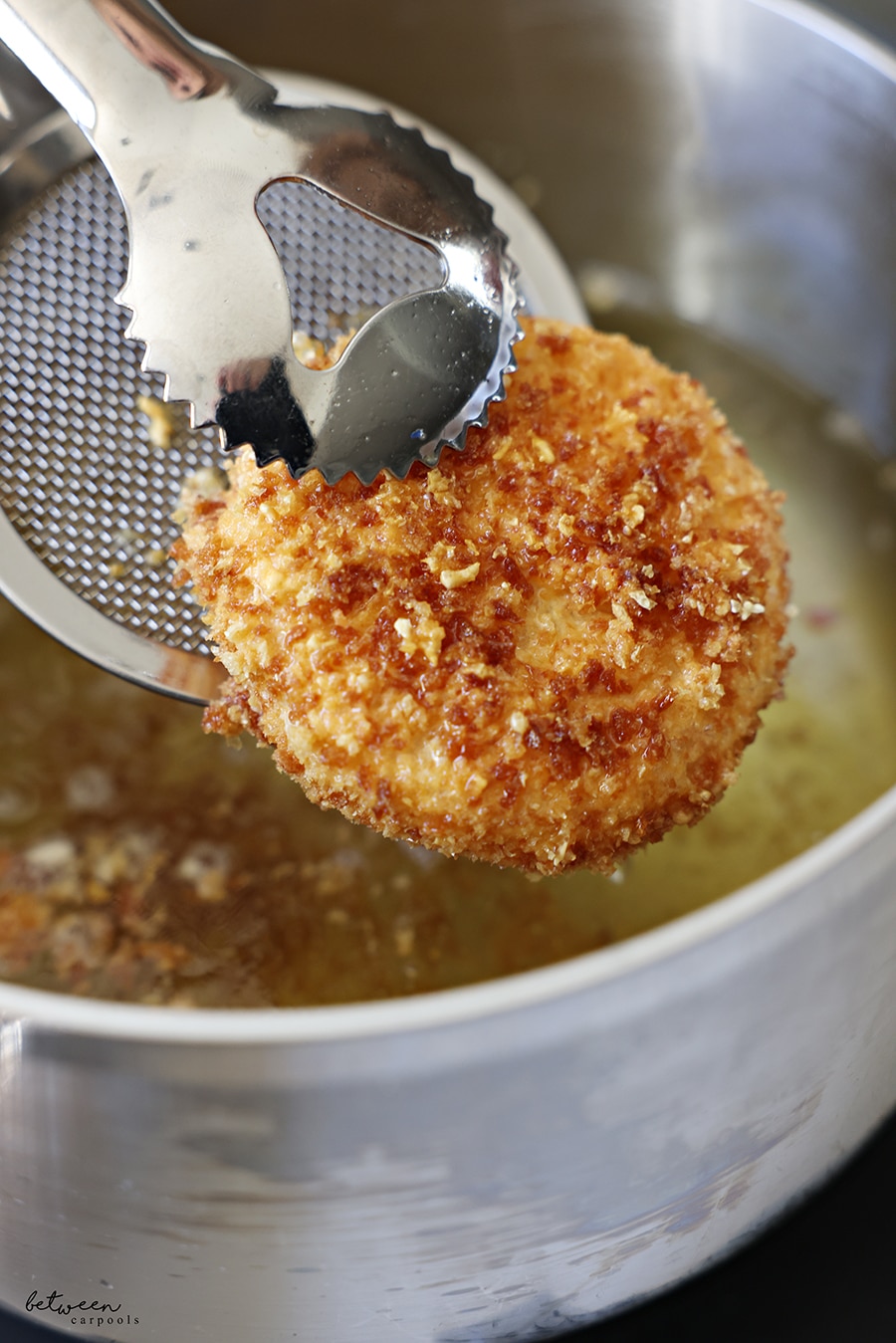 Removing a rice cake with slotted spoon from frying pan.