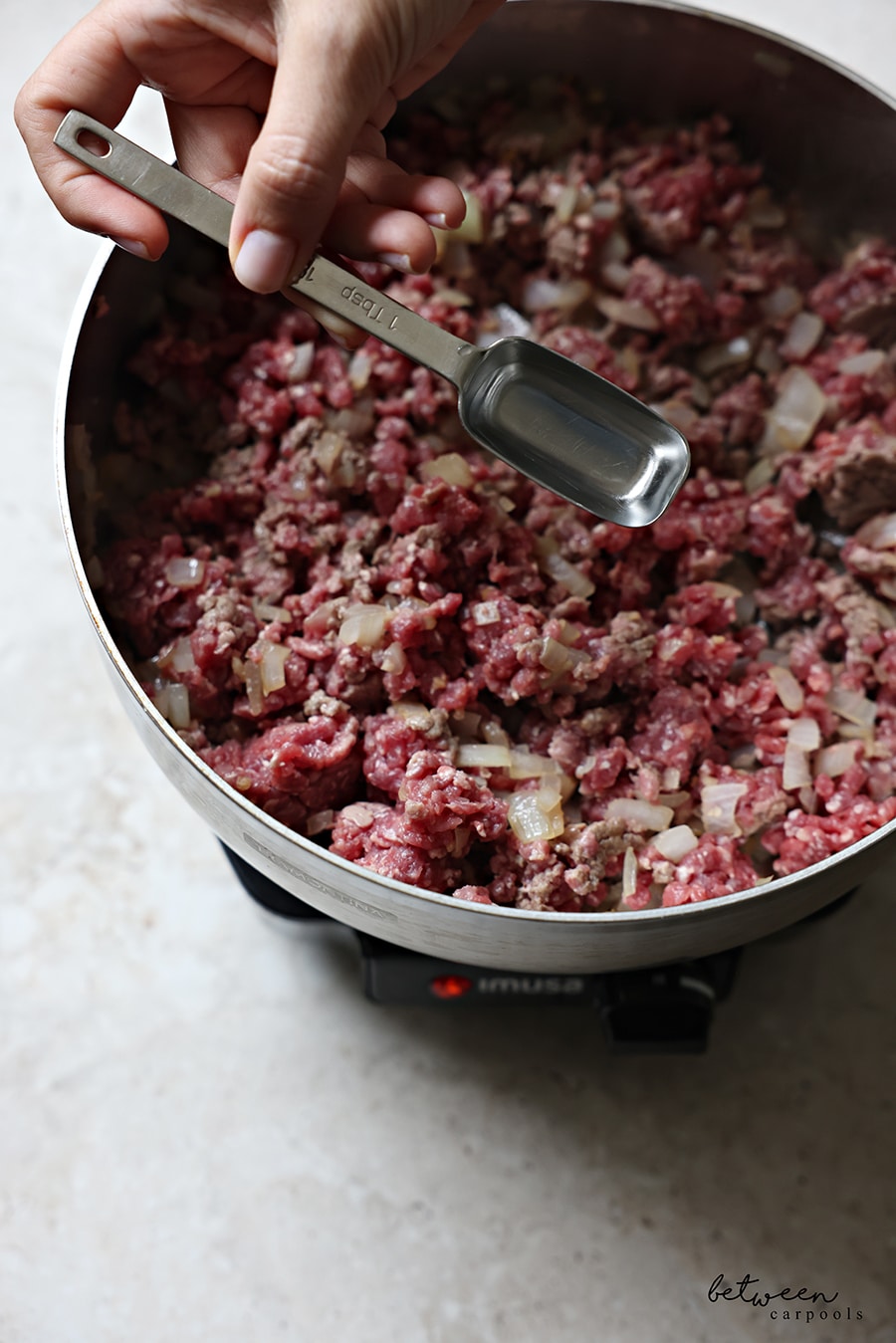 Adding a tbsp of boiling water to ground beef in sauté pan.