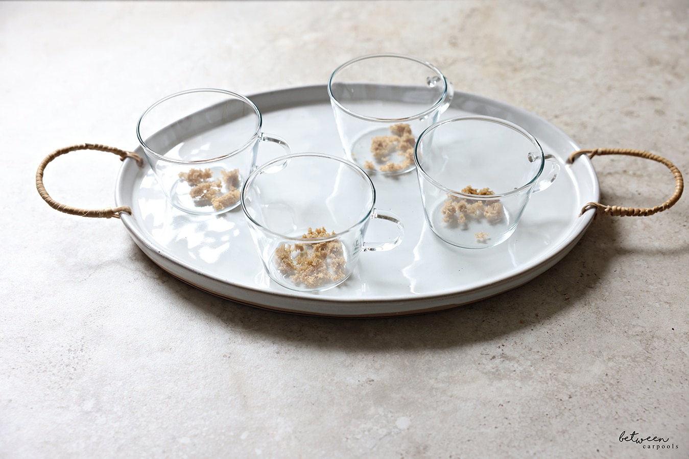 Brown sugar and coffee added to individual glass teacups on a serving tray.