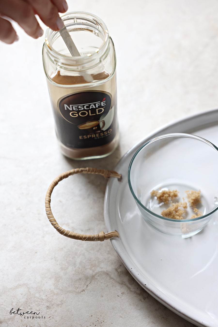 Adding coffee to brown sugar in an individual glass teacup.