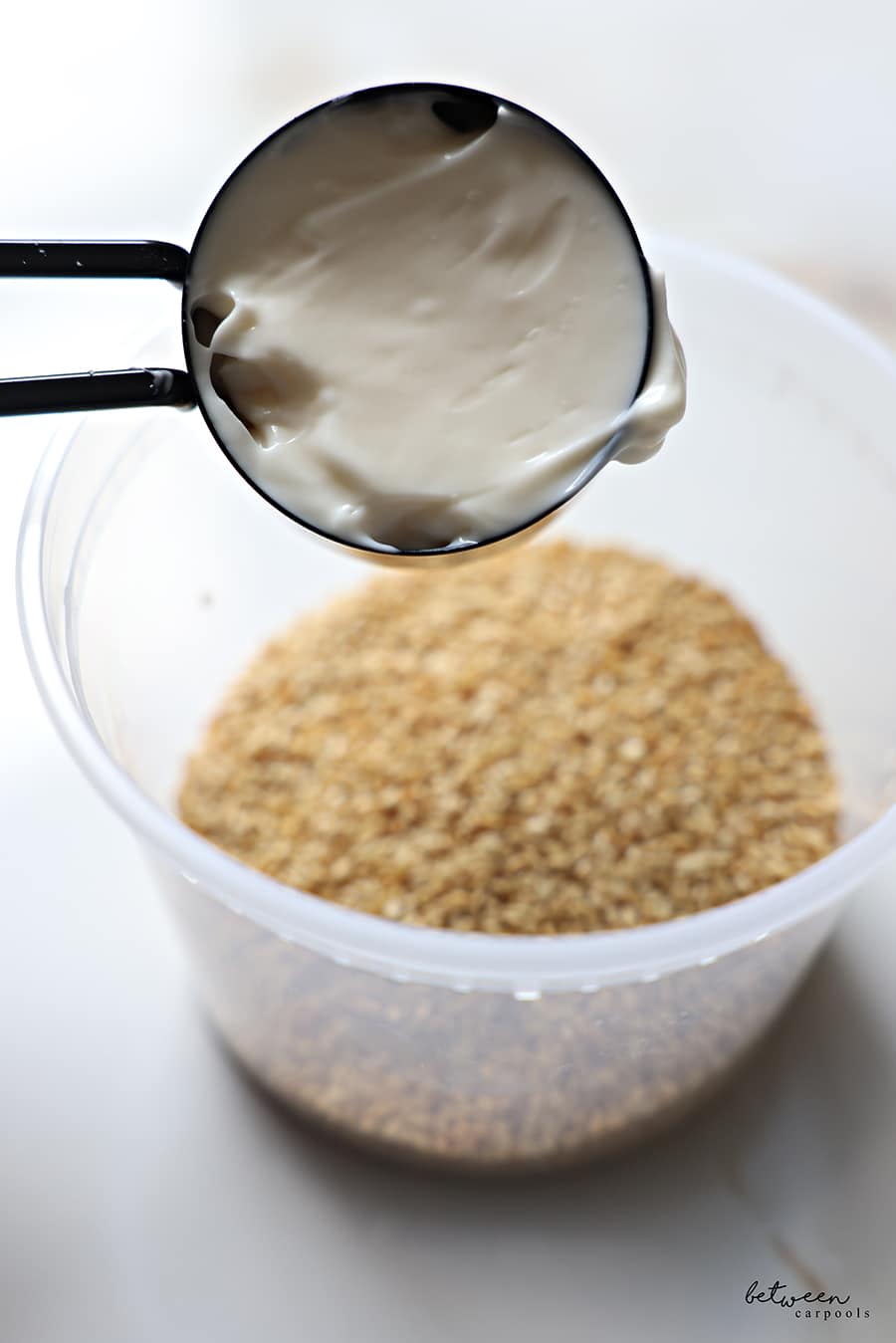 Adding mayo to roasted and cooled sesame seeds in an airtight container.