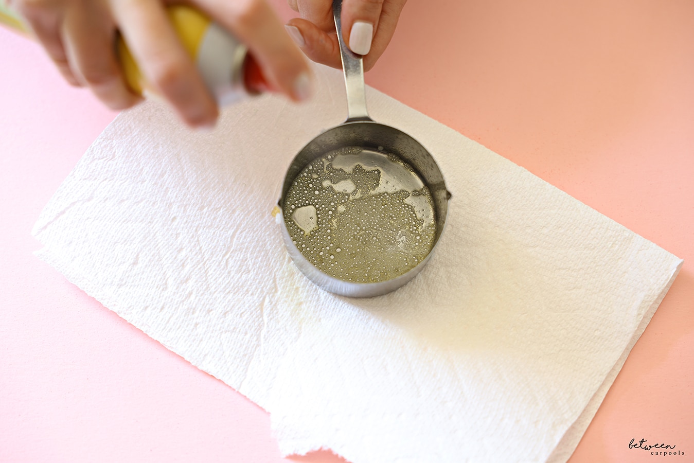 Spraying a measuring cup with oil - on a paper towel