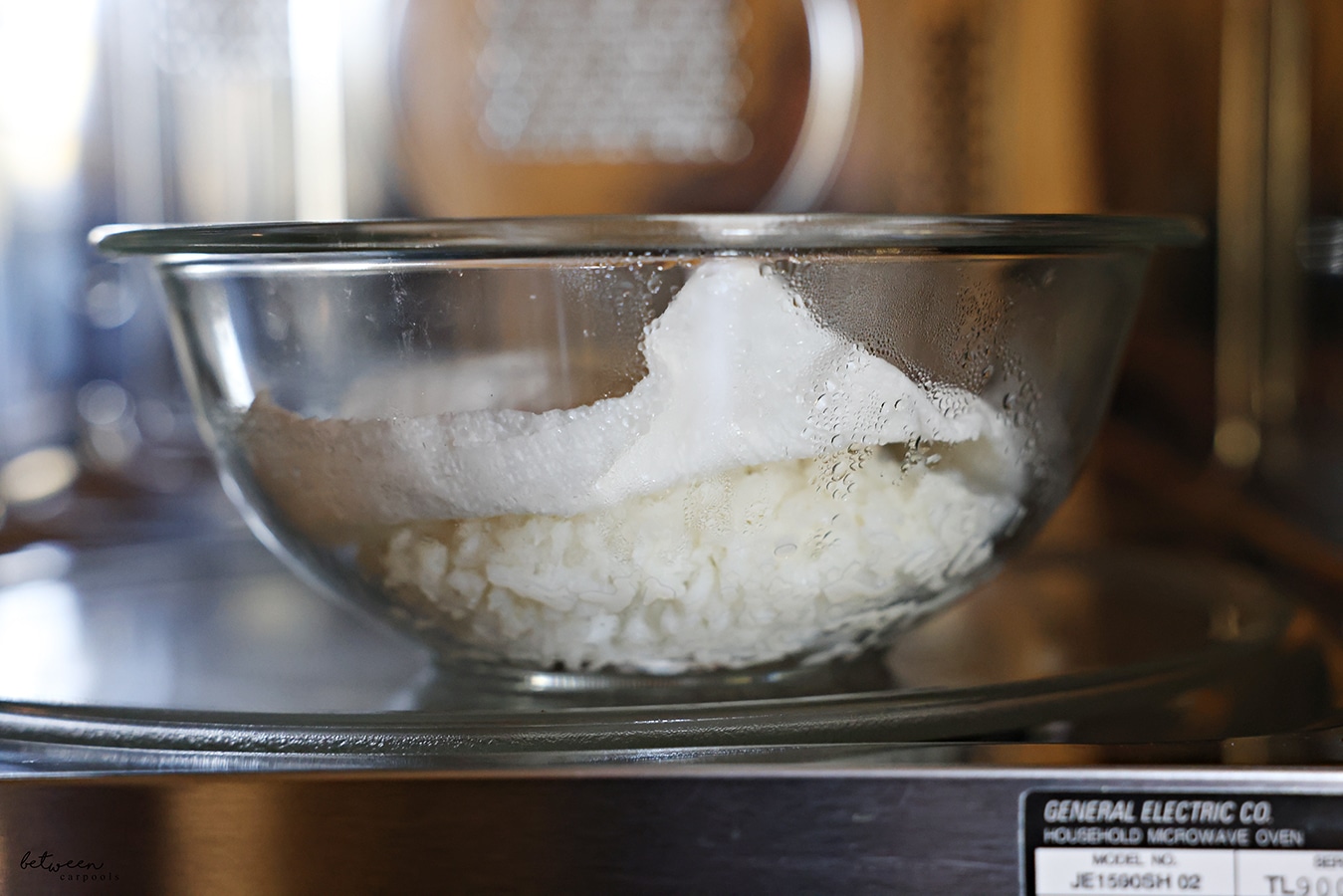 Frozen rice from a Ziploc bag in a microwave safe glass bowl with a damp paper towel on the rice - in the microwave.