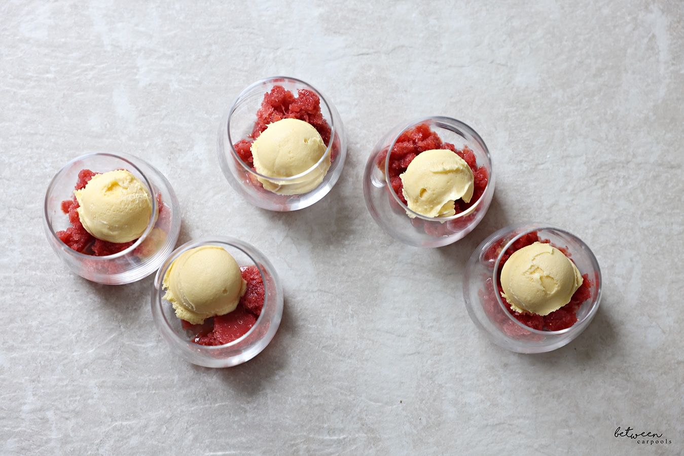 Scoop of pom- strawberry mixture and a scoop of sorbet in individual glass cups - top view.