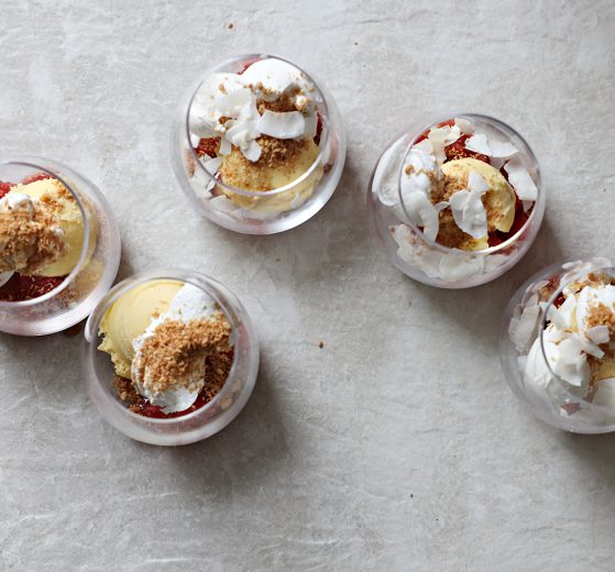 Glass cups with a scoop of pom- strawberry mixture, a scoop of sorbet, Coco Whip, coconut chips and nut crunch.