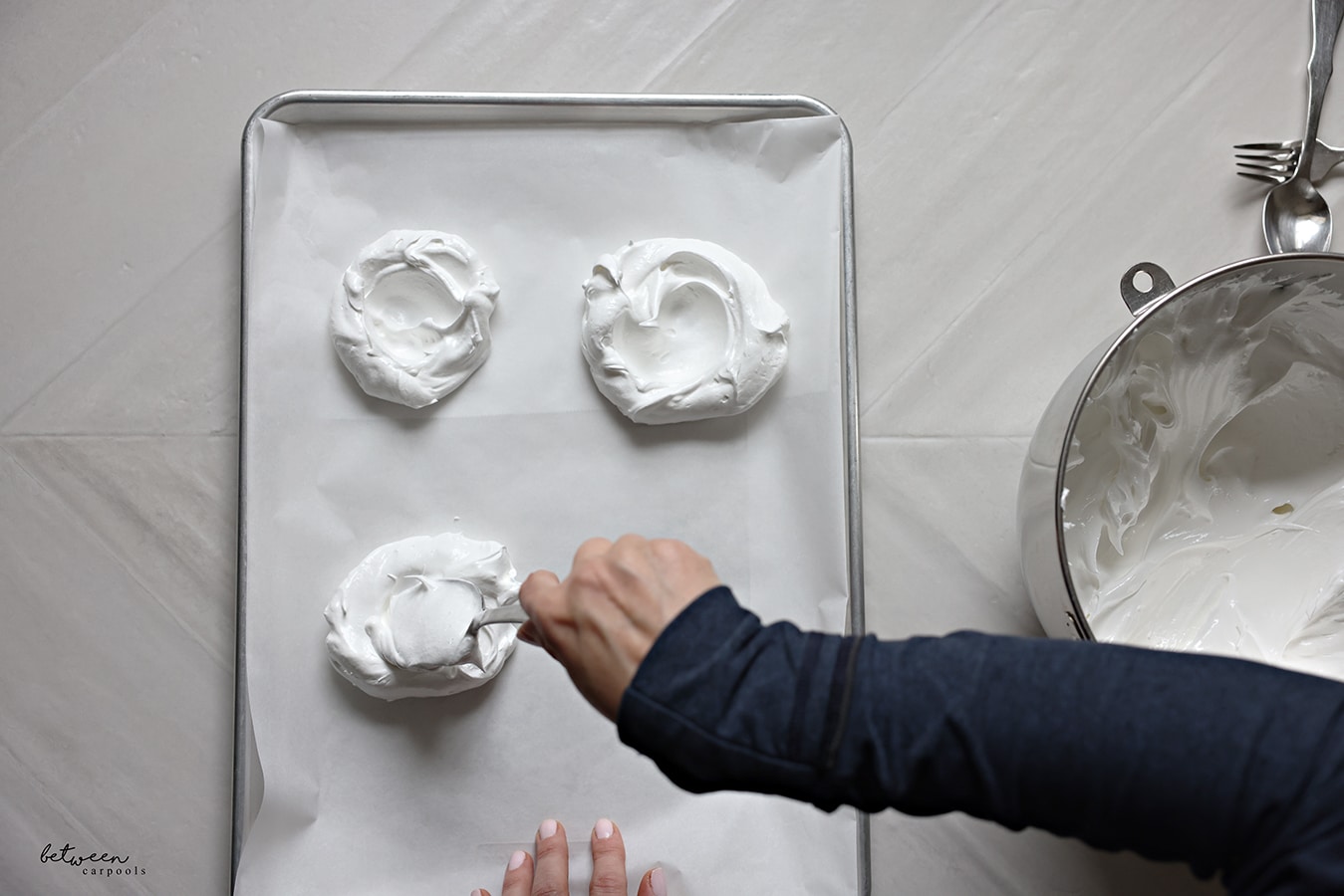 Creating a well in each meringue nest with a spoon.