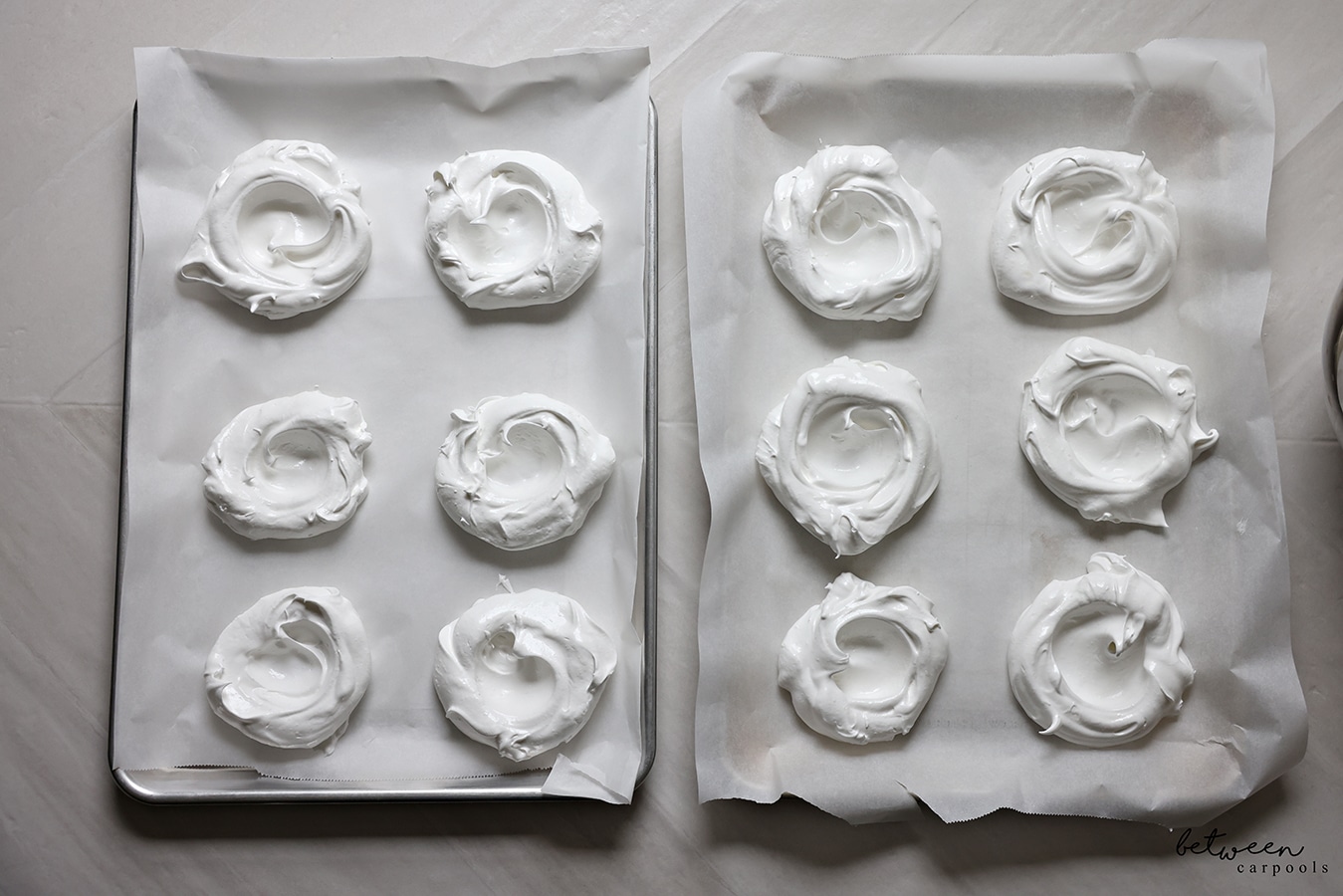 Baked meringue pavlovas on 2 parchment lined baking sheets. 6 meringues per sheet.