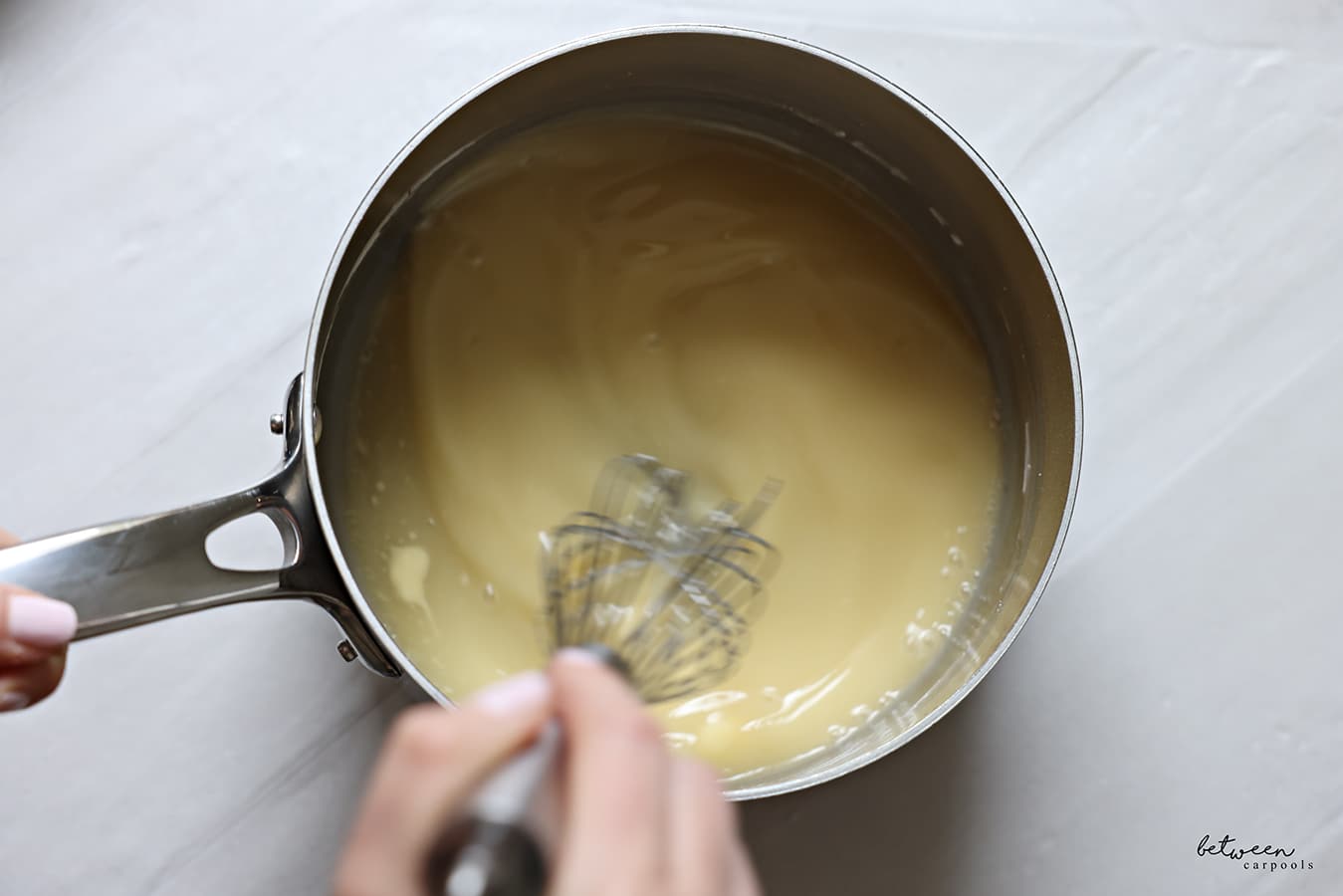 Whisking lemon curd in a saucepan.
