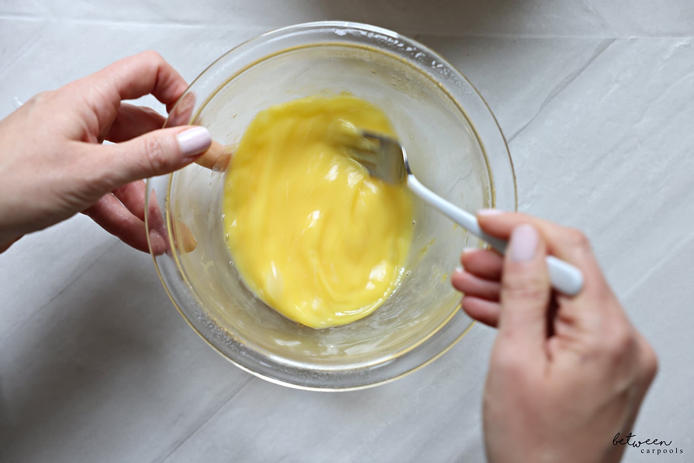 Whisking together egg and yolks in a bowl.