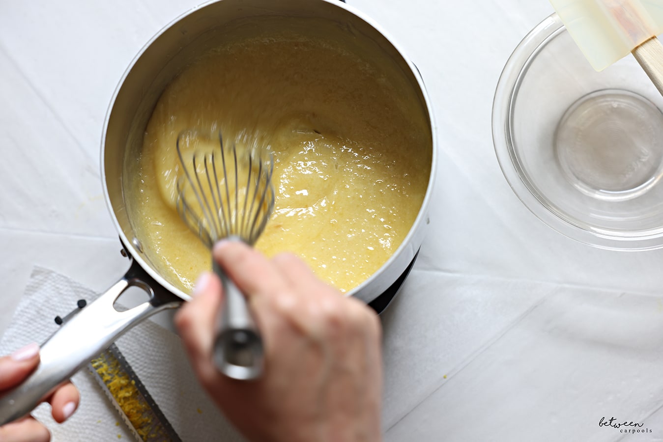 Whisking the thickening curd in a pot.