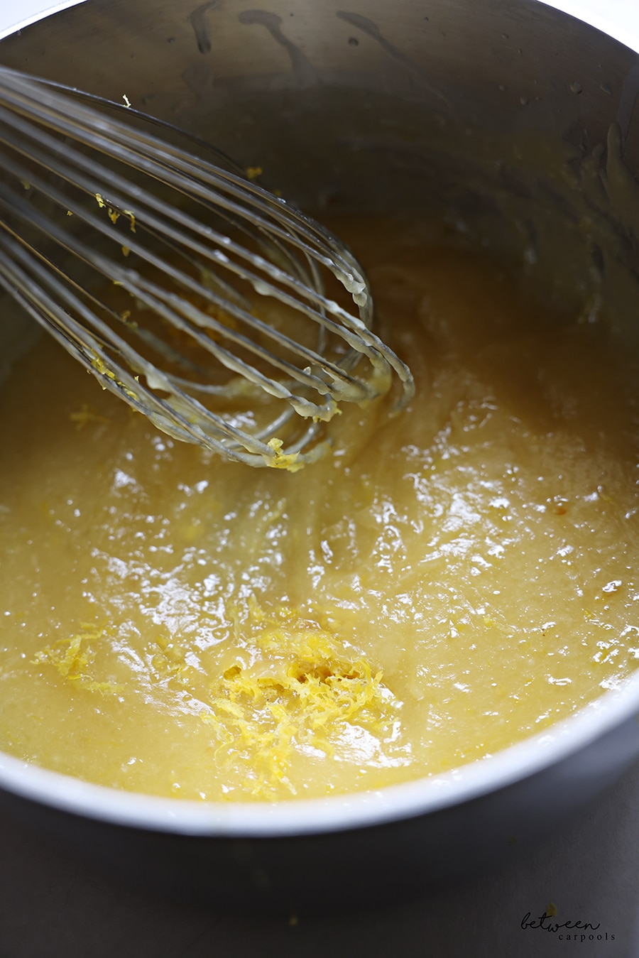 Lemon zest added to the lemon curd in a pot.