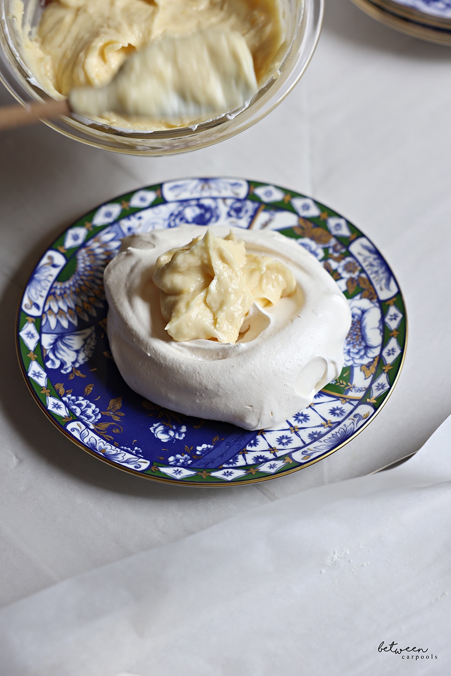 Pavlova/meringue on a dessert plate, topped with a generous spoonful of lemon curd. 