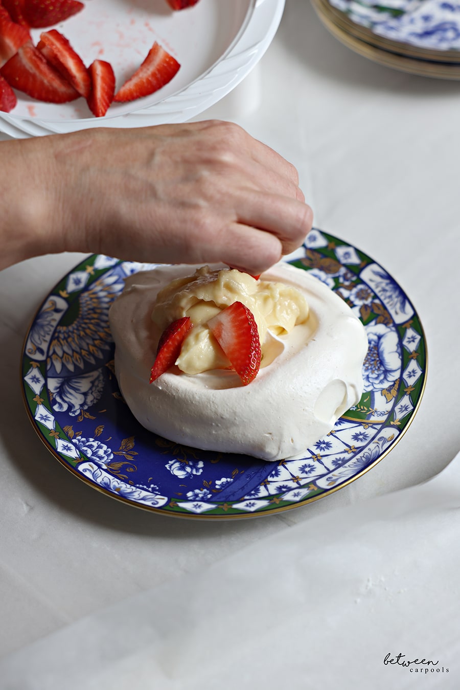 Adding berries to pavlova with lemon curd.
